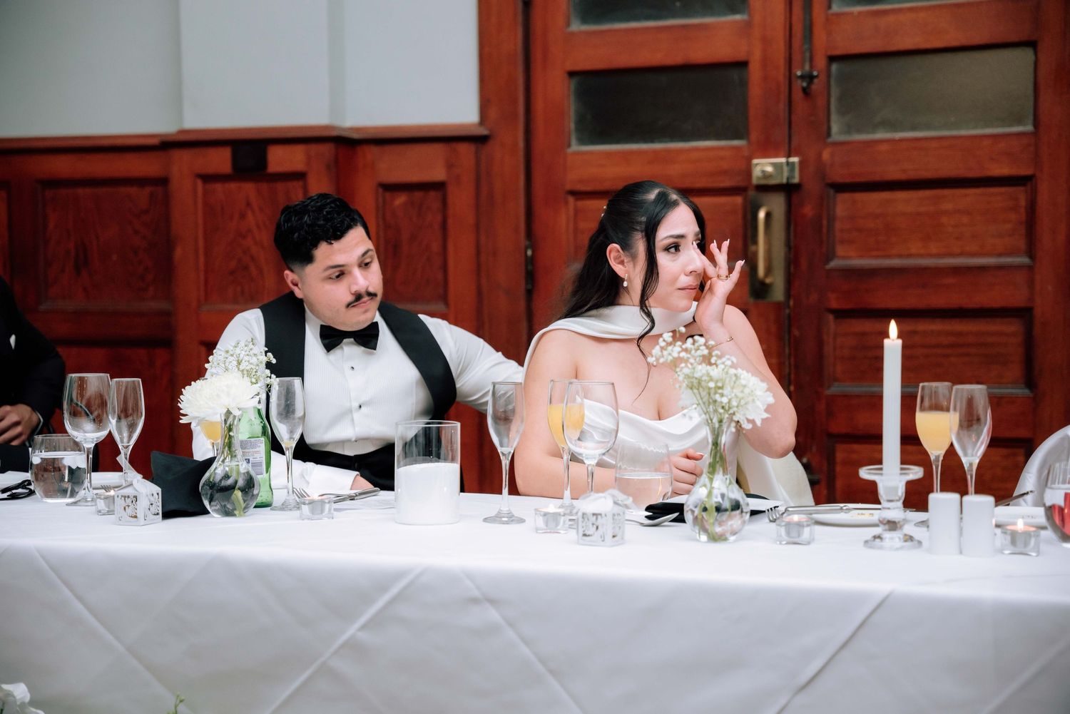 Bride and groom sharing a lighthearted moment at the head table during wedding reception dinner.