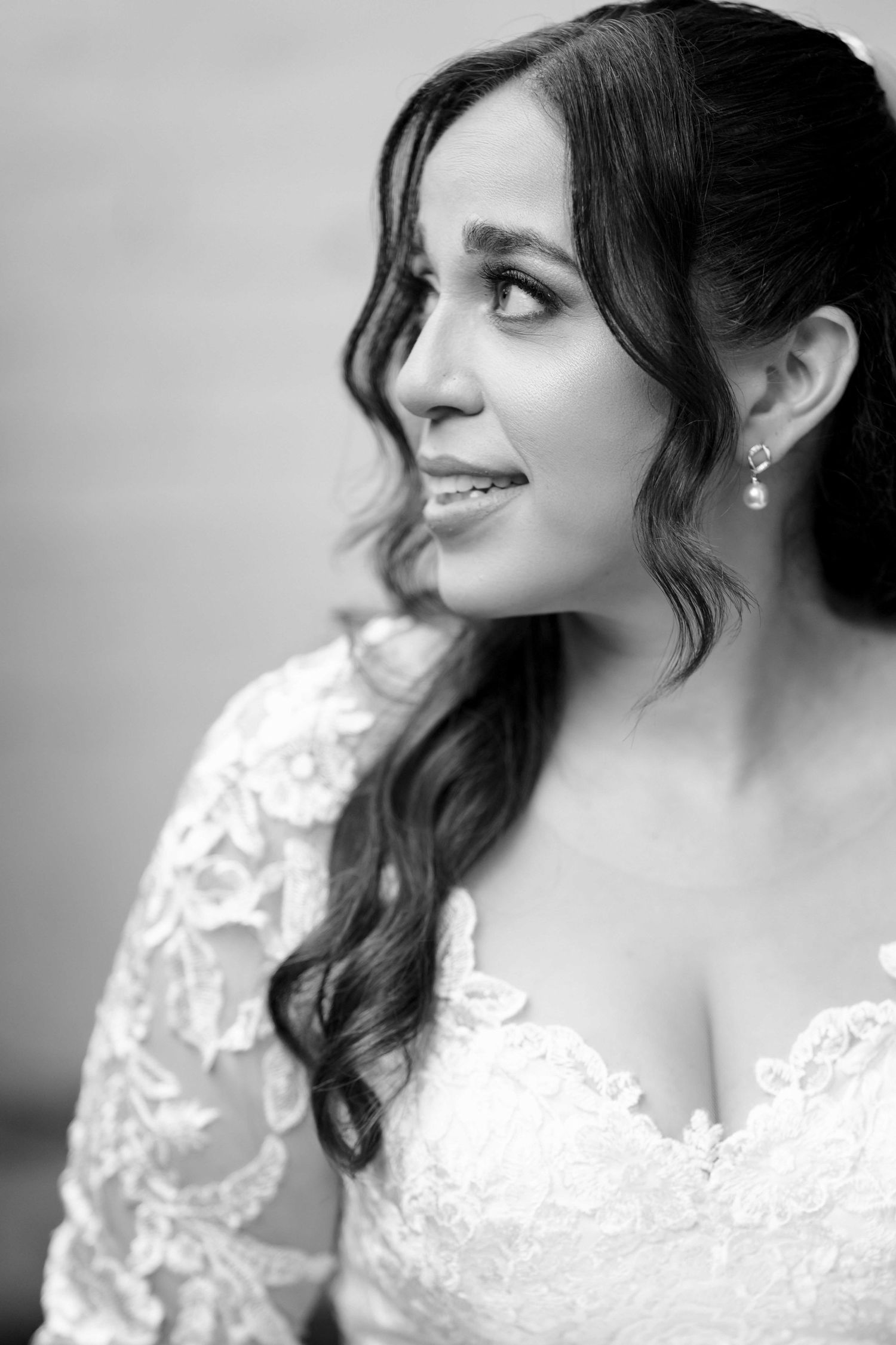 Elegant black and white bridal portrait of bride in lace wedding gown with pearl drop earrings.