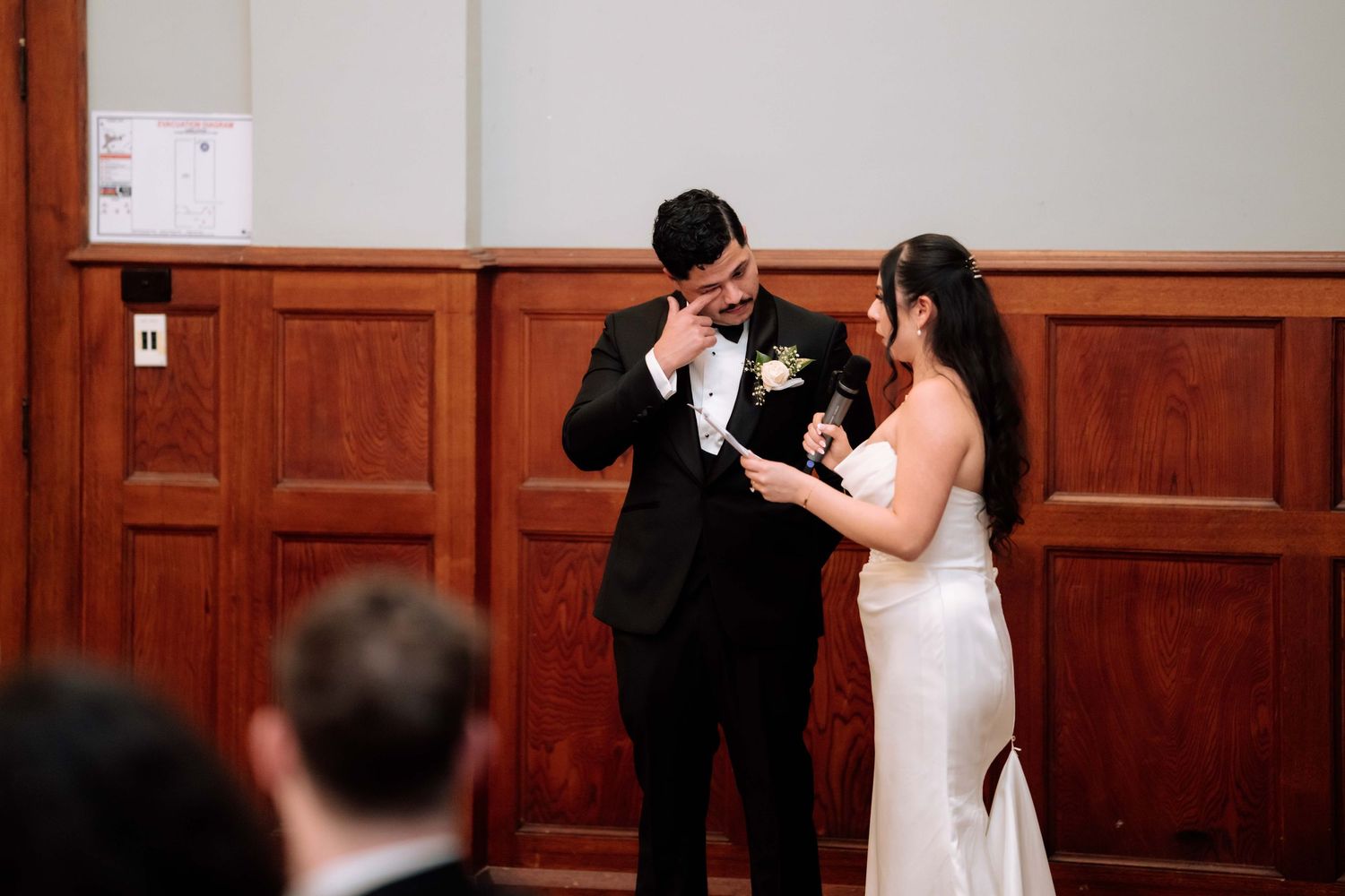 A groom wipes tears during an emotional moment with his bride at their intimate wedding ceremony.