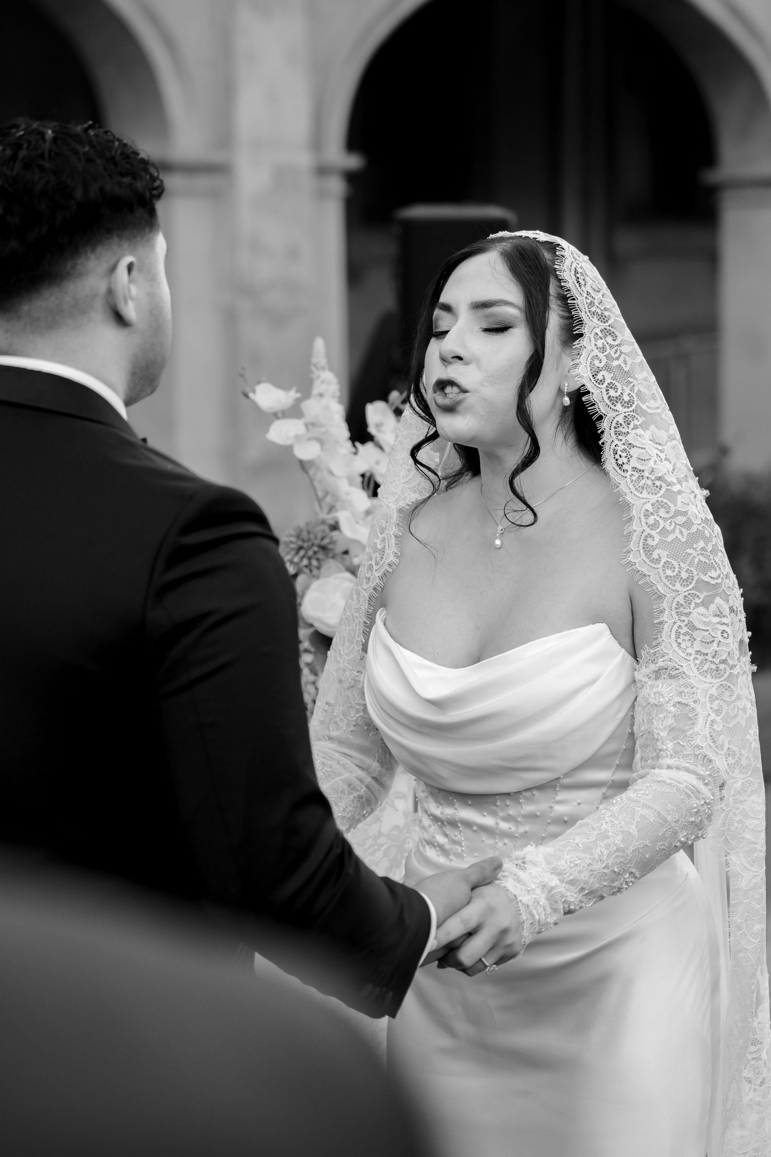 Bride reciting vows to groom in black and white wedding ceremony portrait.