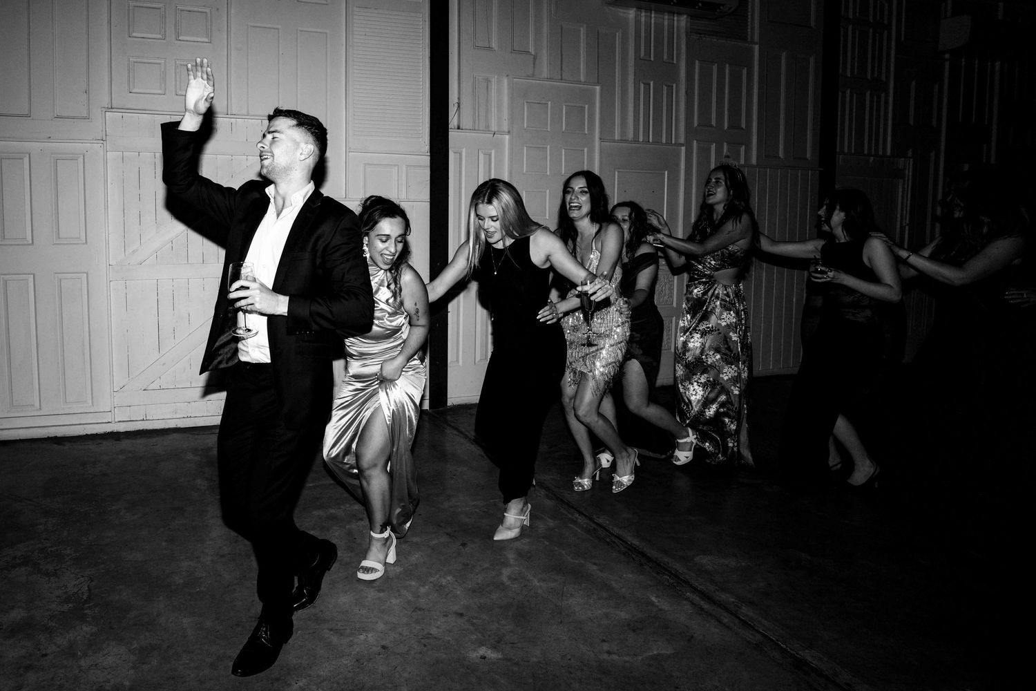 Guests dancing energetically at a wedding reception in black and white photo.