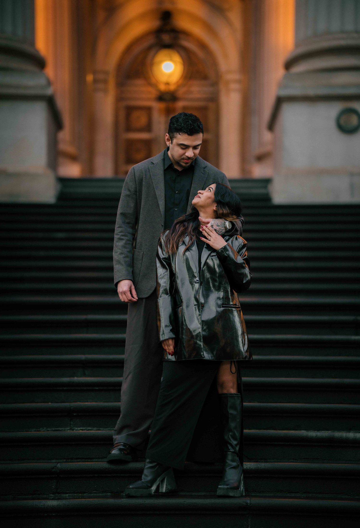 Couple sharing an intimate moment on grand stone steps of a classical building at dusk.