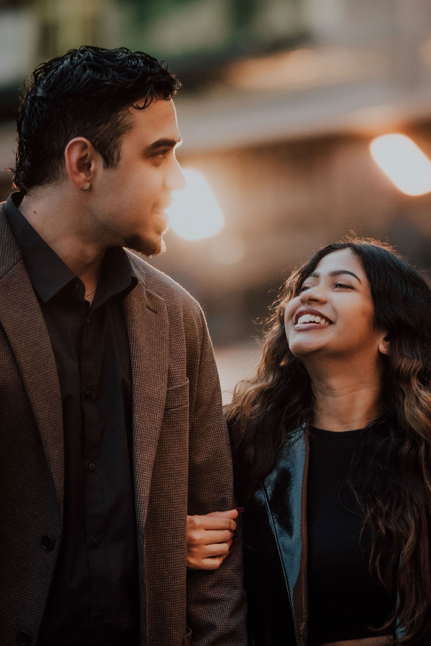 Close-up of smiling couple sharing a joyful moment with bokeh city lights behind.