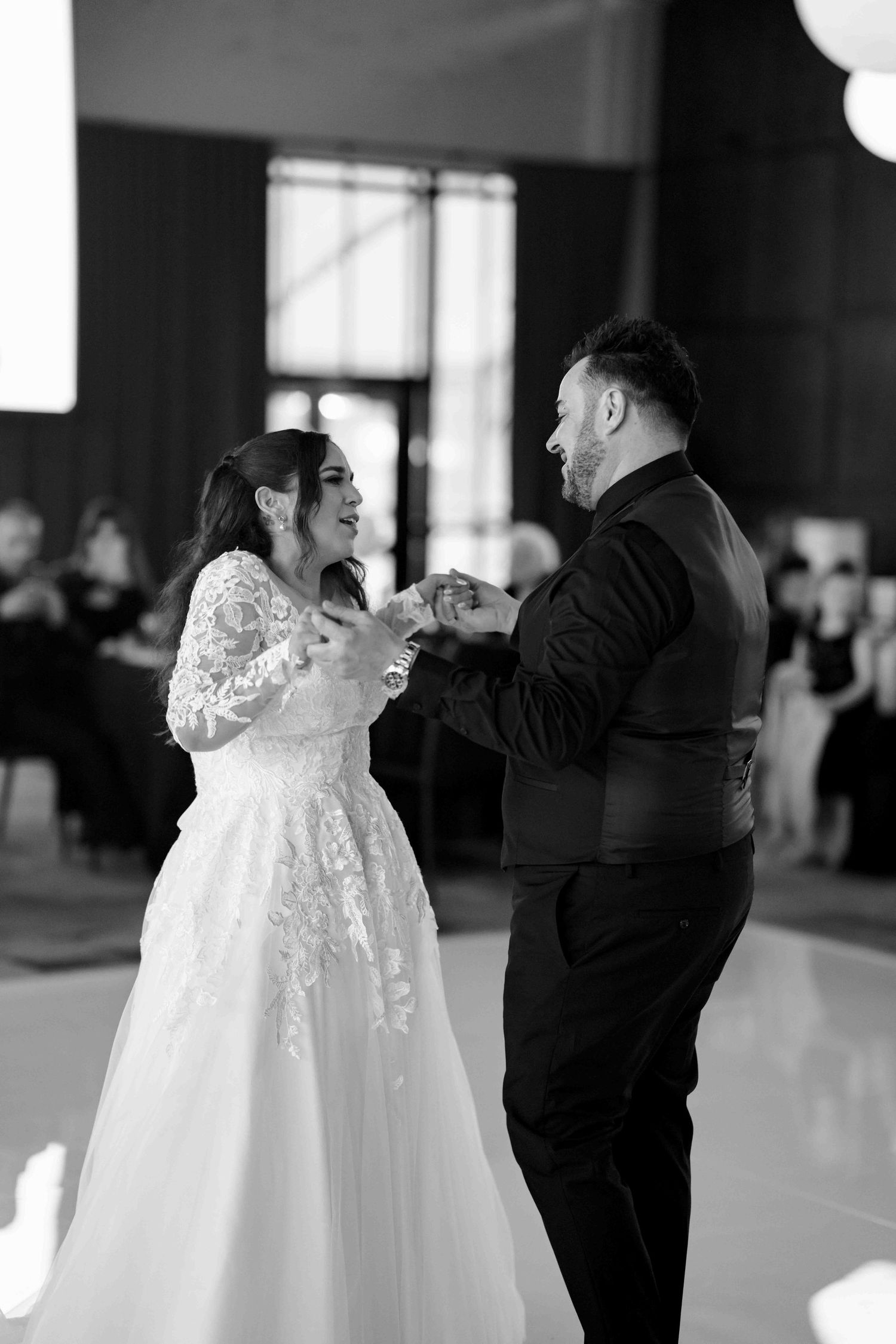 Black and white photo of bride and groom sharing their first dance at elegant wedding reception.