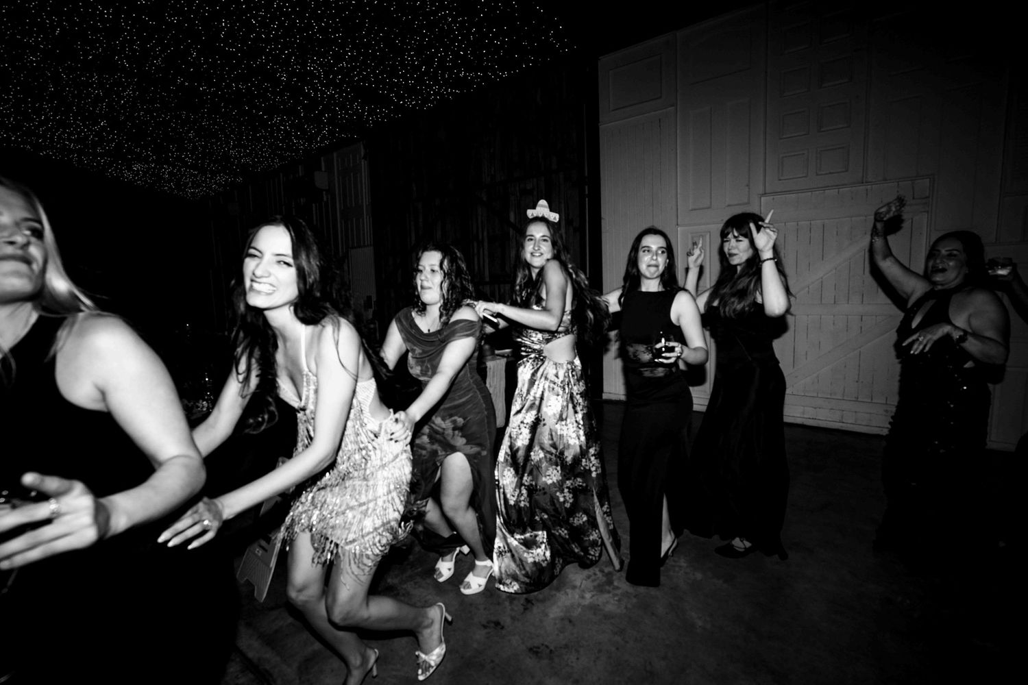 Black and white photo of women dancing and celebrating at a wedding reception party.