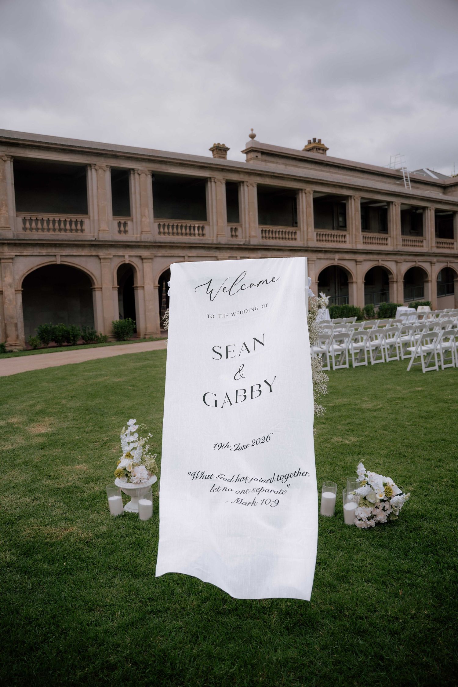 Elegant outdoor wedding welcome sign for Sean and Gabby with white chairs and floral arrangements.