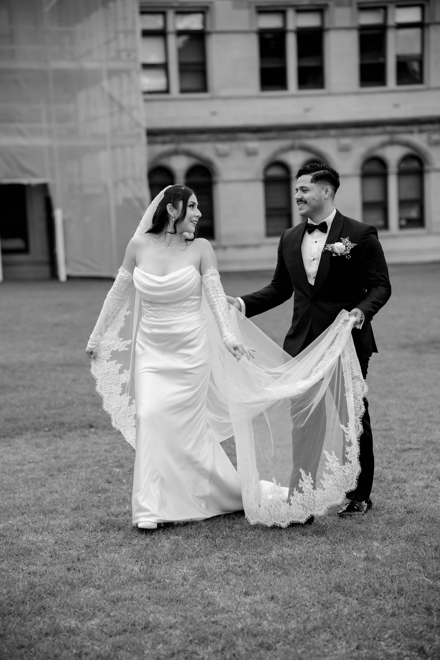 Bride and groom walking together in black and white wedding portrait outdoors.