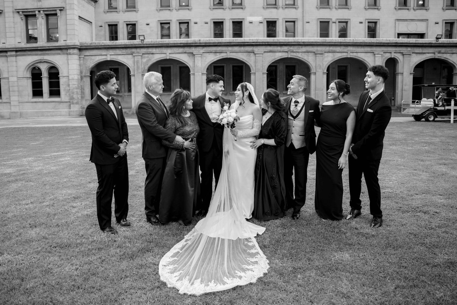 Wedding party group portrait in black and white with bride and groom outdoors.