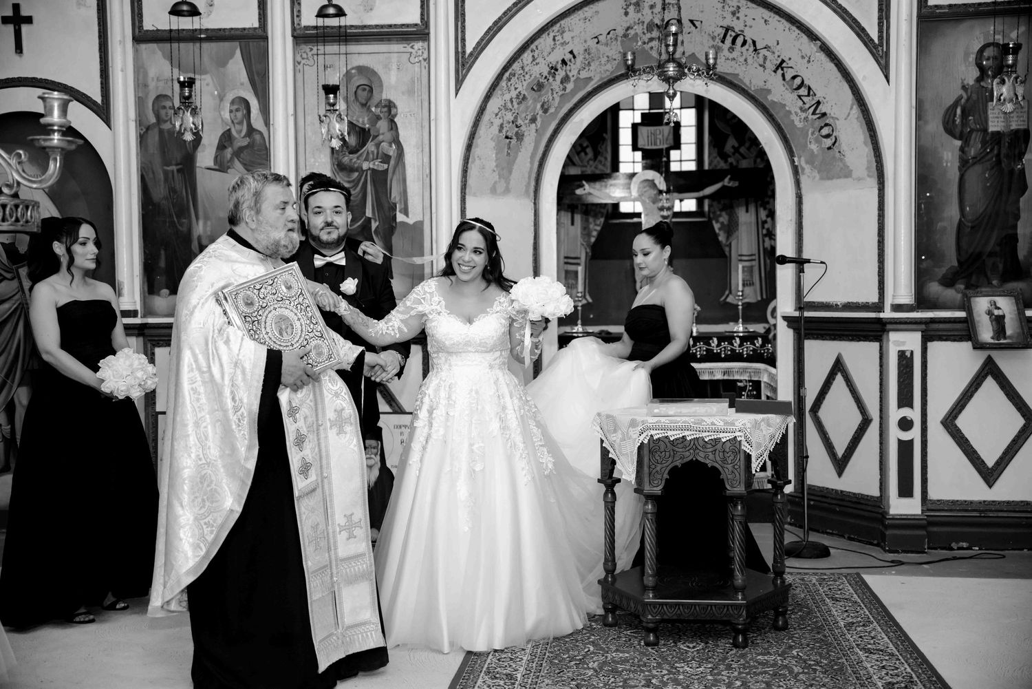 Greek Orthodox priest performs wedding ceremony with bride and groom at church altar.