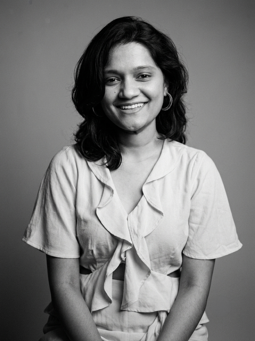 Black and white portrait of a smiling young woman in a ruffled blouse, studio photography.