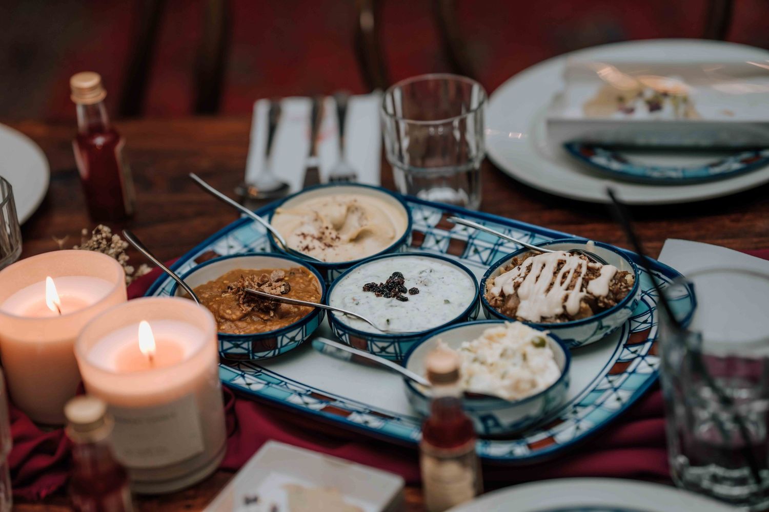 Wedding dessert plate with assorted sweets and dips surrounded by glowing candles on rustic table.