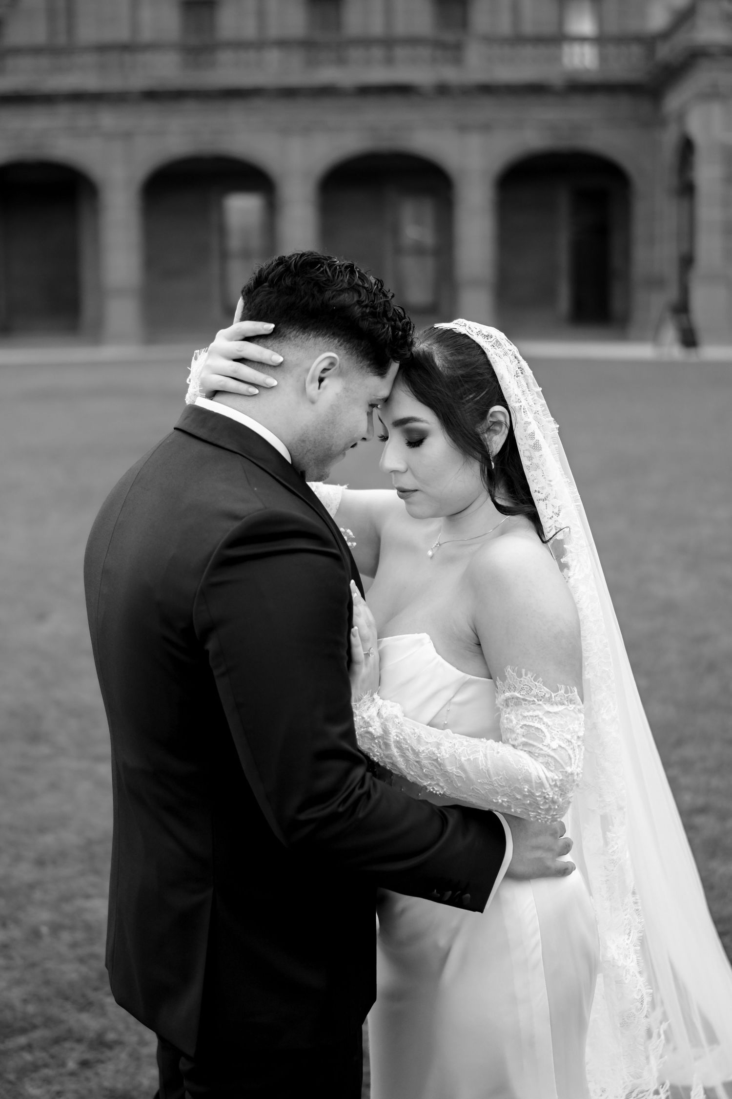 Black and white photo of bride and groom sharing intimate moment in courtyard.