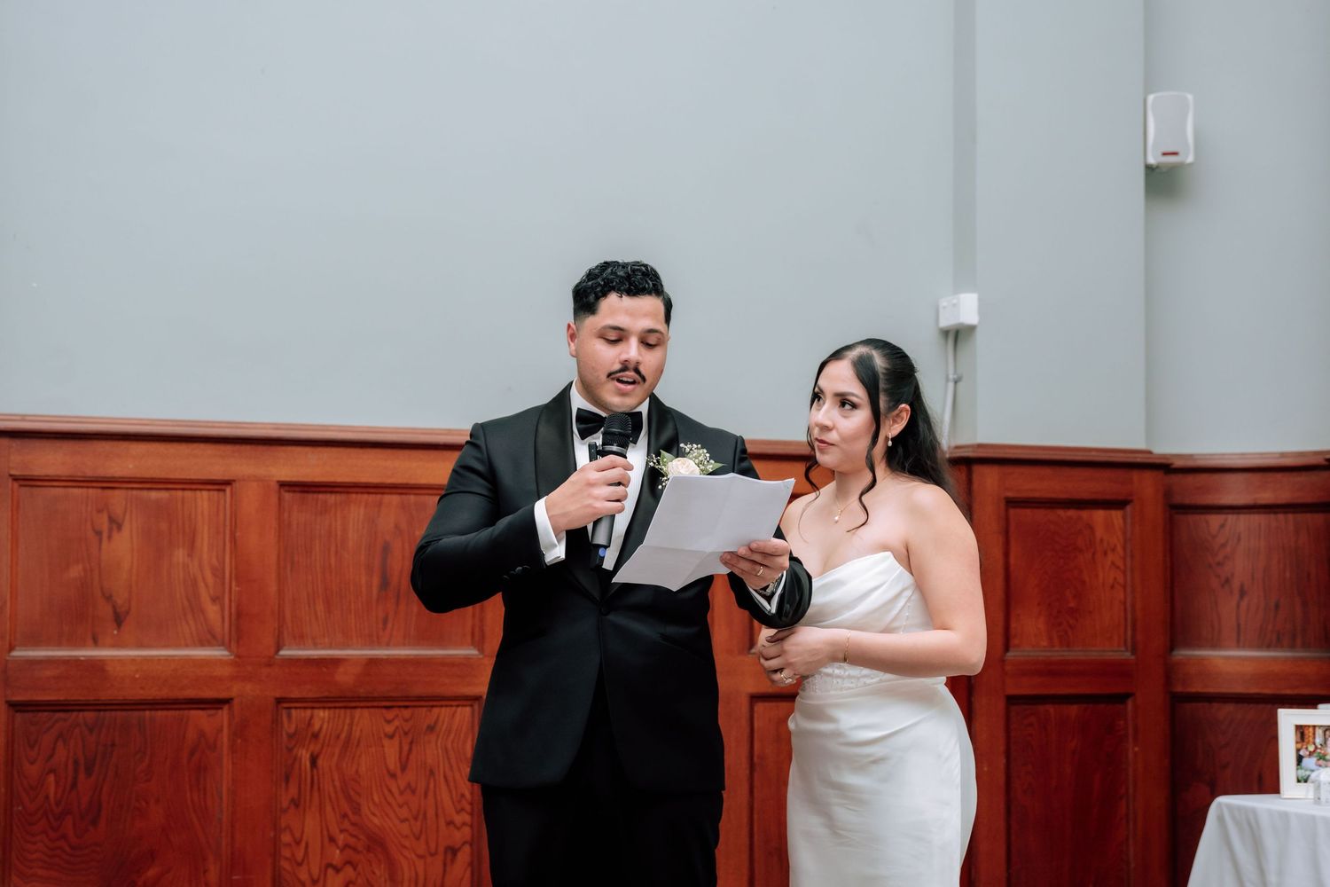 Bride and groom reading vows together at wedding ceremony with microphone.