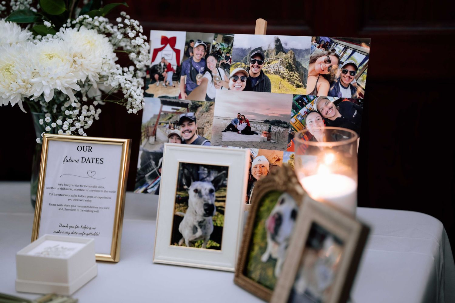 Wedding reception memory table displaying couple's photos, white flowers, and a candle centerpiece.