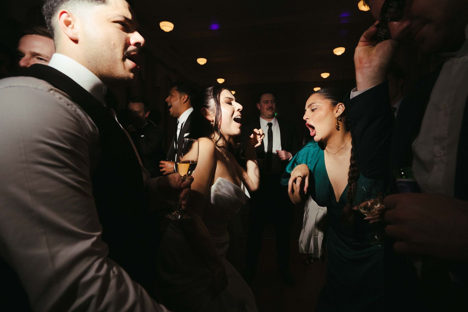 Bride and guests singing and dancing joyfully at wedding reception party.