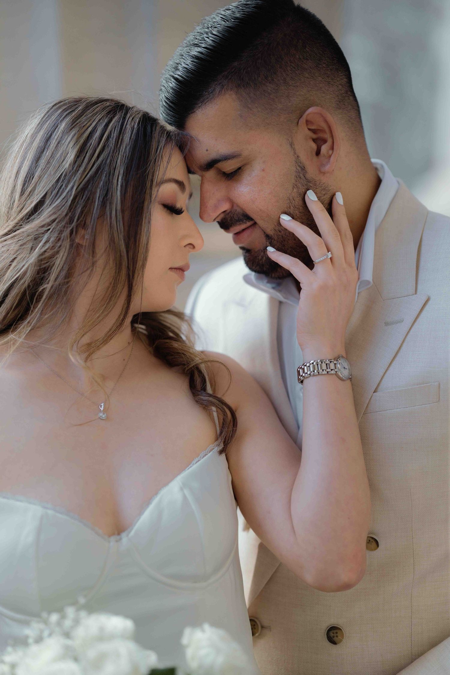 Intimate close-up of a bride tenderly touching her grooms face as they share a romantic moment together.