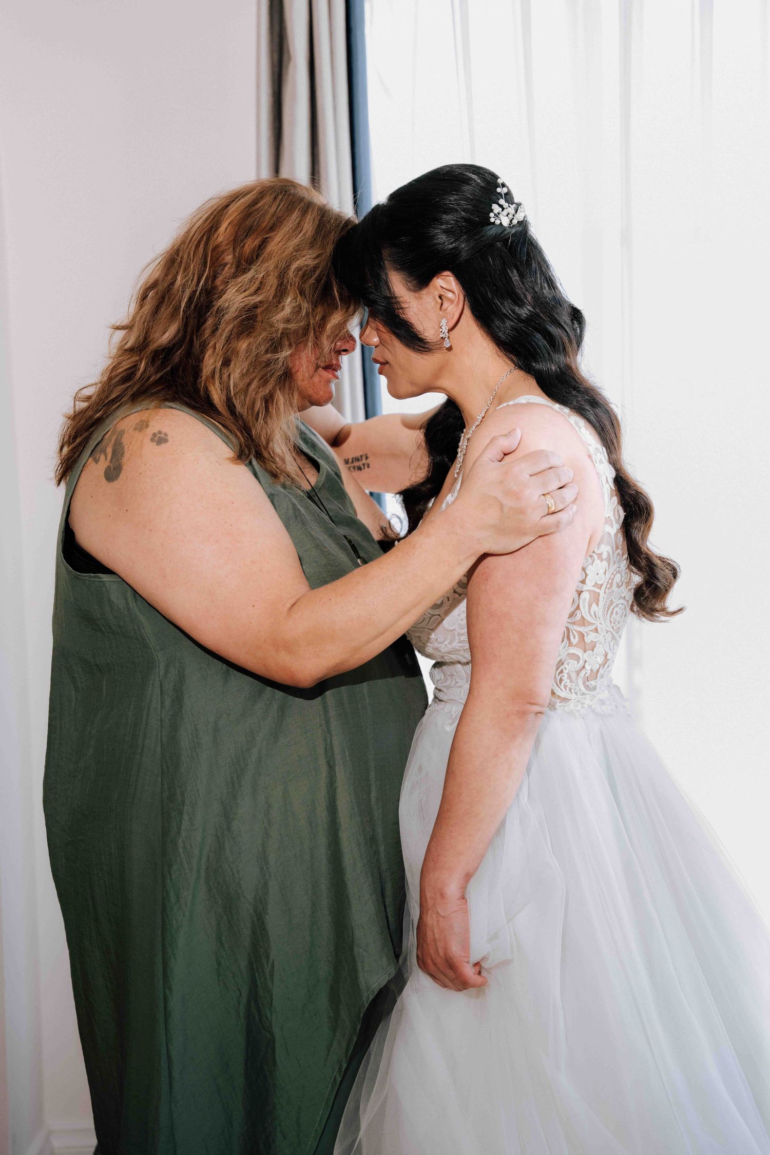 Emotional mother and bride sharing an intimate forehead touch moment during wedding morning preparations.