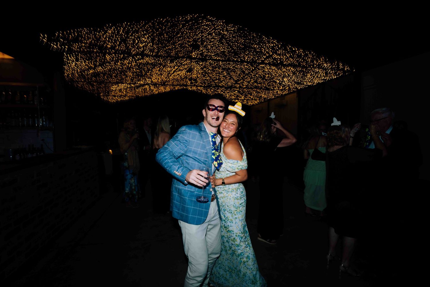 Couple dancing under twinkling fairy lights at a wedding reception party.