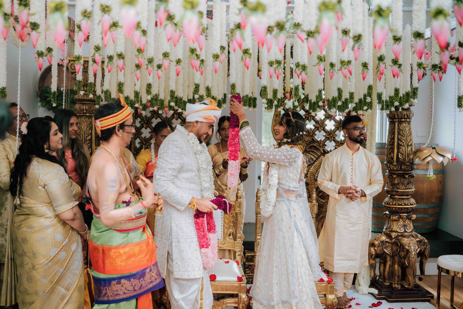 Indian wedding ceremony moment at an ornate mandap with guests and priest performing traditional Hindu wedding rituals.