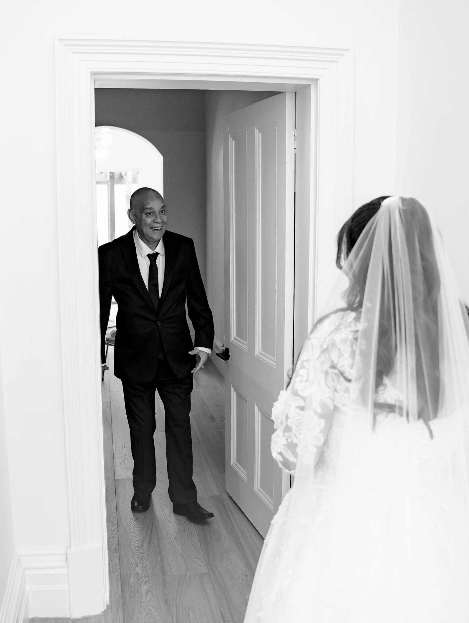 Emotional father sees bride daughter in wedding dress for first look moment.