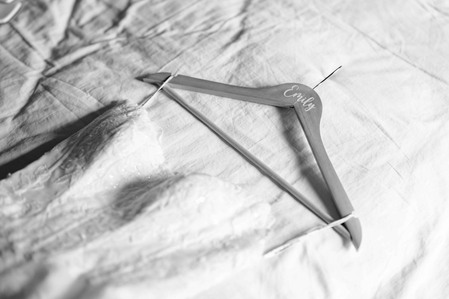 Personalized wooden wedding hanger with bride's name in cursive on white linen background.
