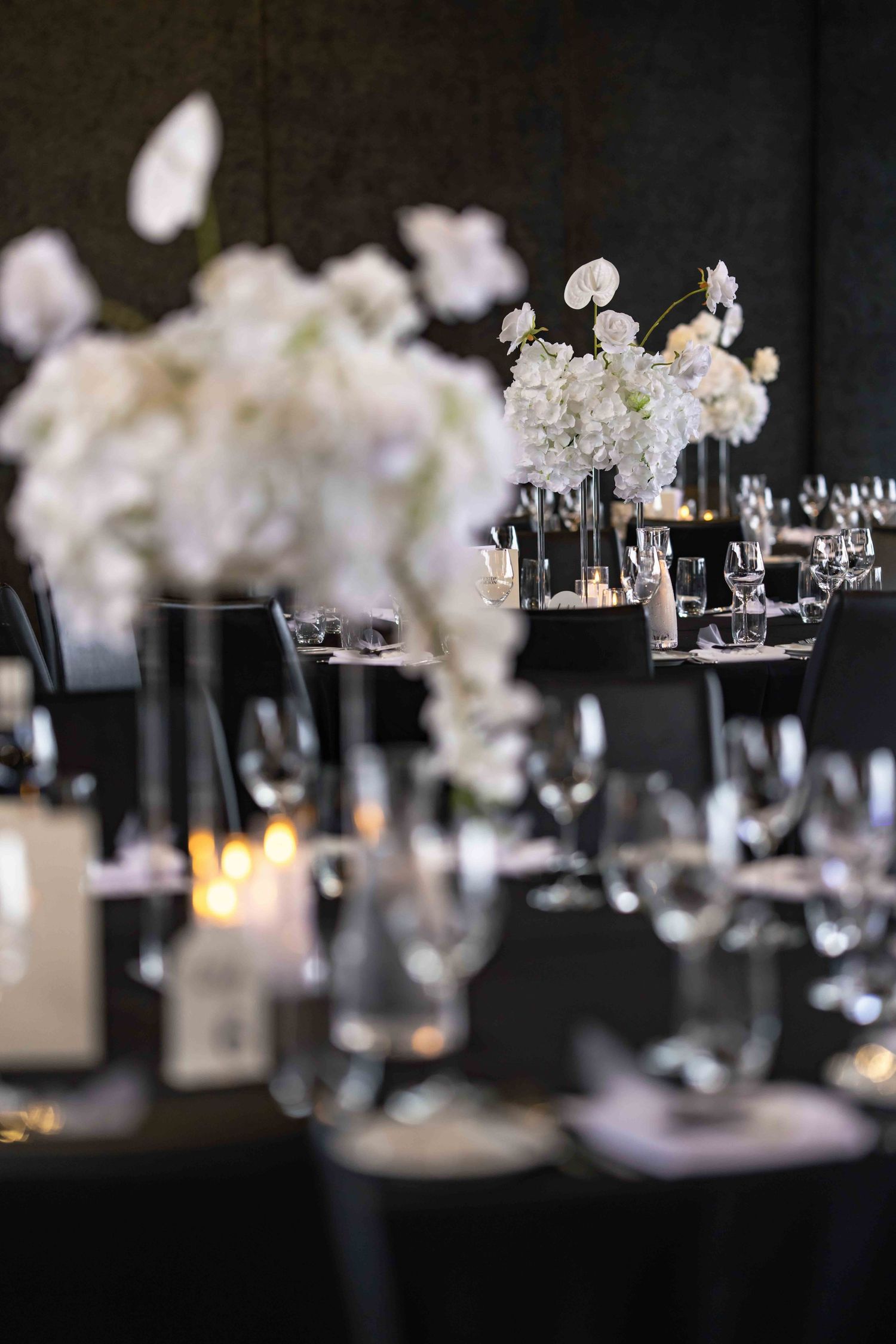 Elegant wedding reception table with white floral centerpieces and candlelight decor.