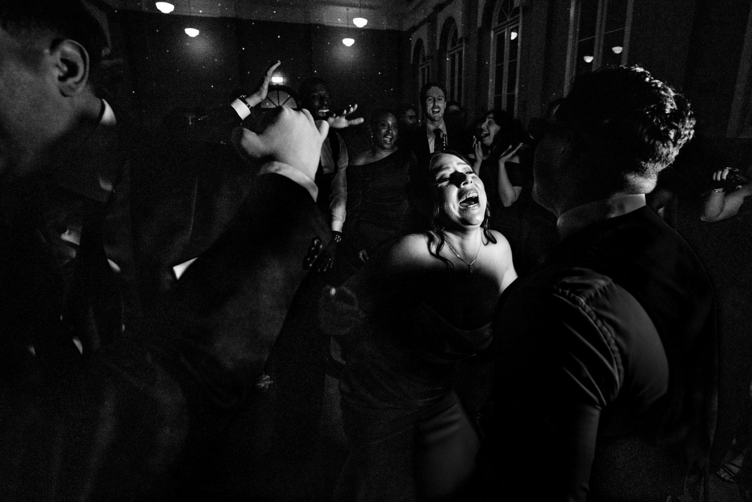 Black and white photo of guests dancing energetically on the wedding reception dance floor.