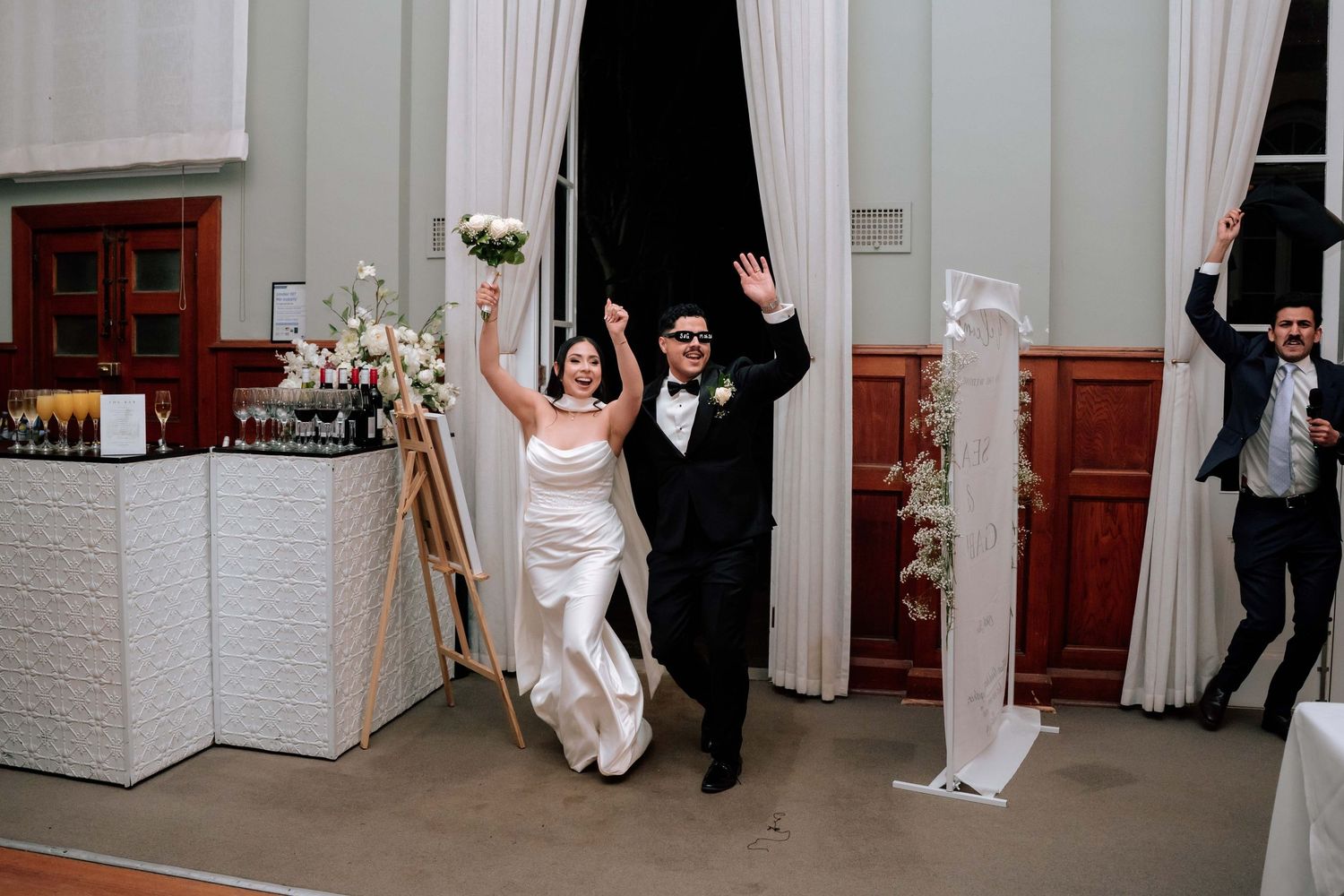 Bride and groom make a joyful grand entrance into their wedding reception hall.