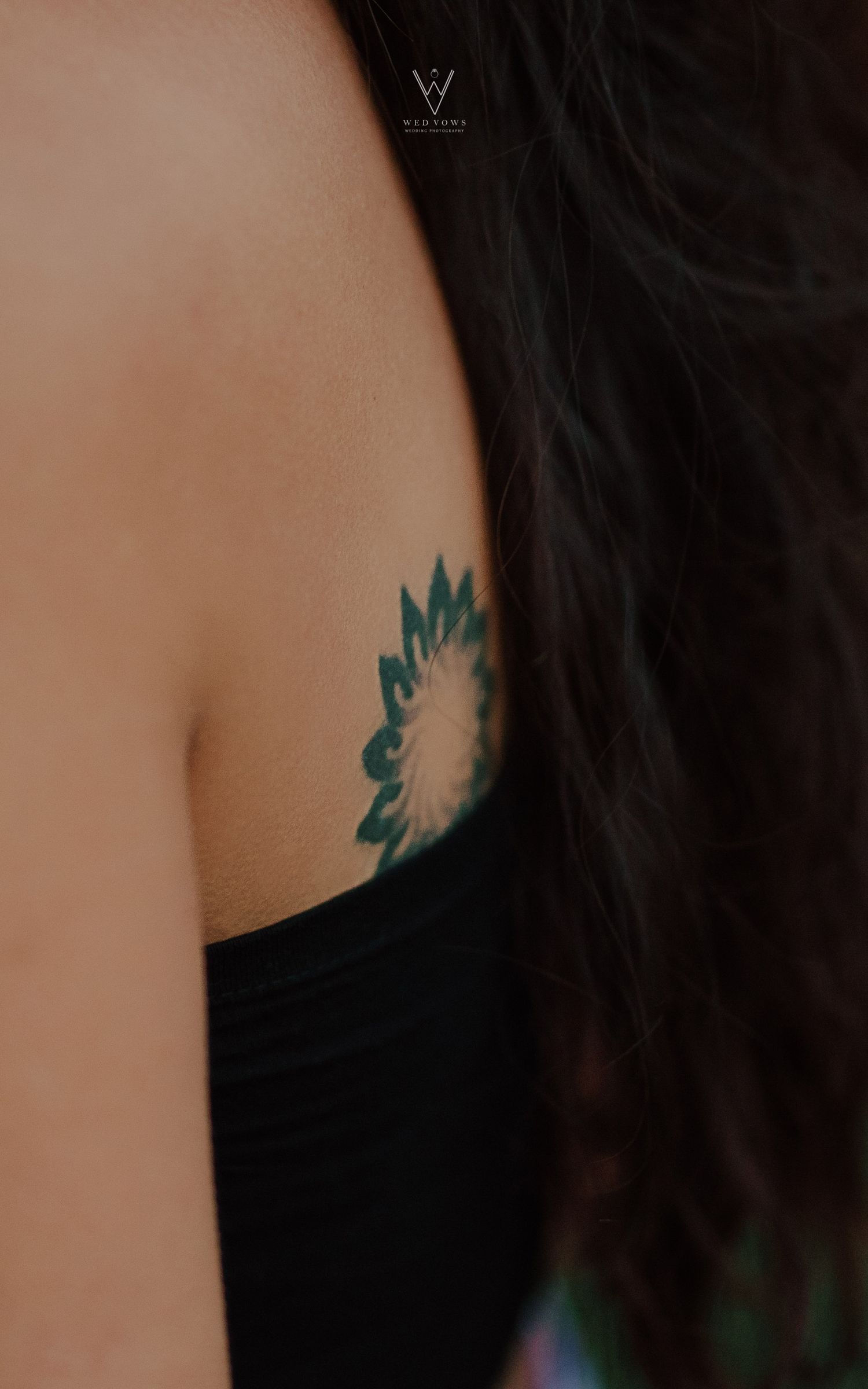 Close-up of woman's shoulder featuring a detailed mandala sunflower tattoo in teal.