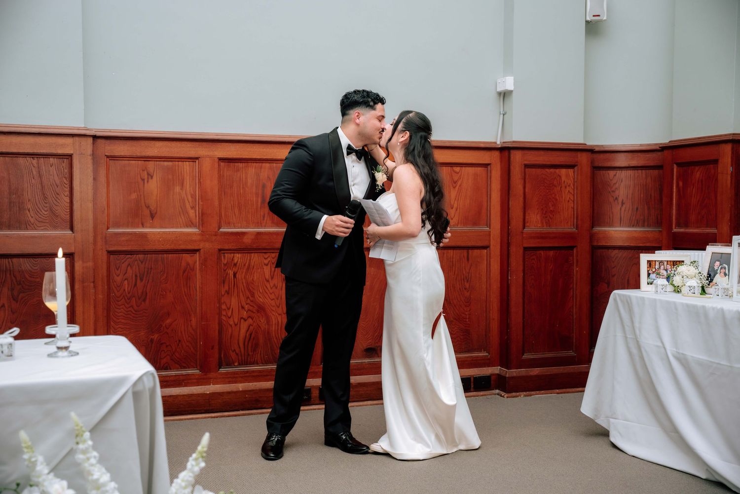Newlyweds share a tender first kiss as husband and wife at their elegant wedding reception.