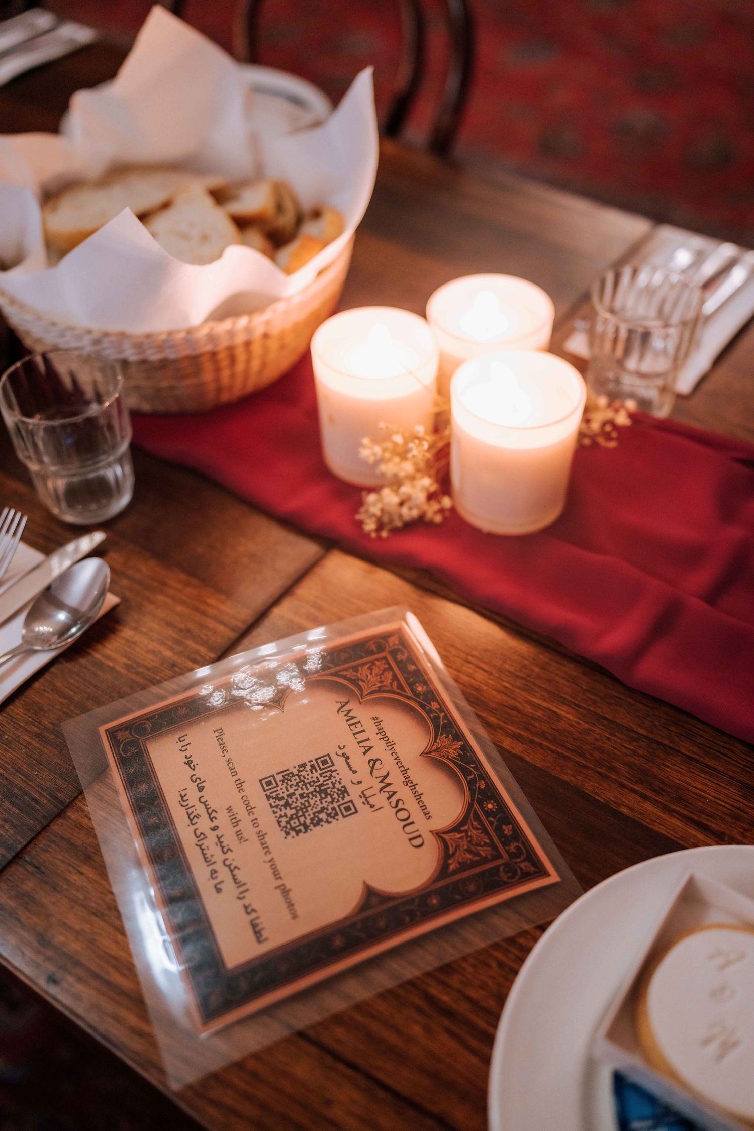 Wedding table setting with candles, bread basket, QR code menu card, and red table runner.
