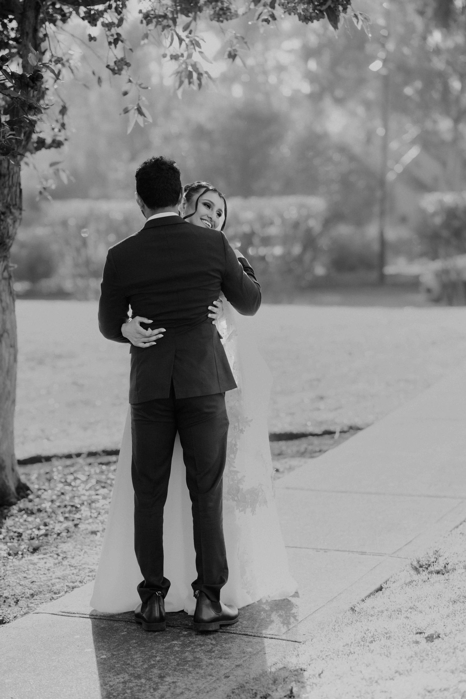 Black and white photo of bride and groom sharing tender embrace outdoors on wedding day.
