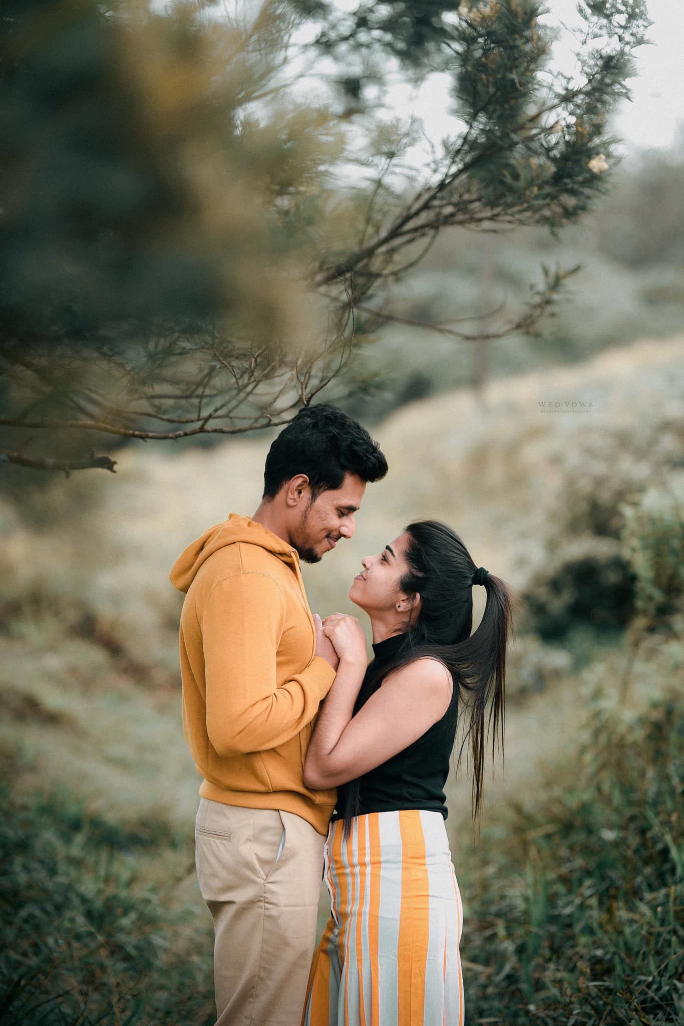 Couple gazing lovingly at each other in a misty outdoor nature setting.