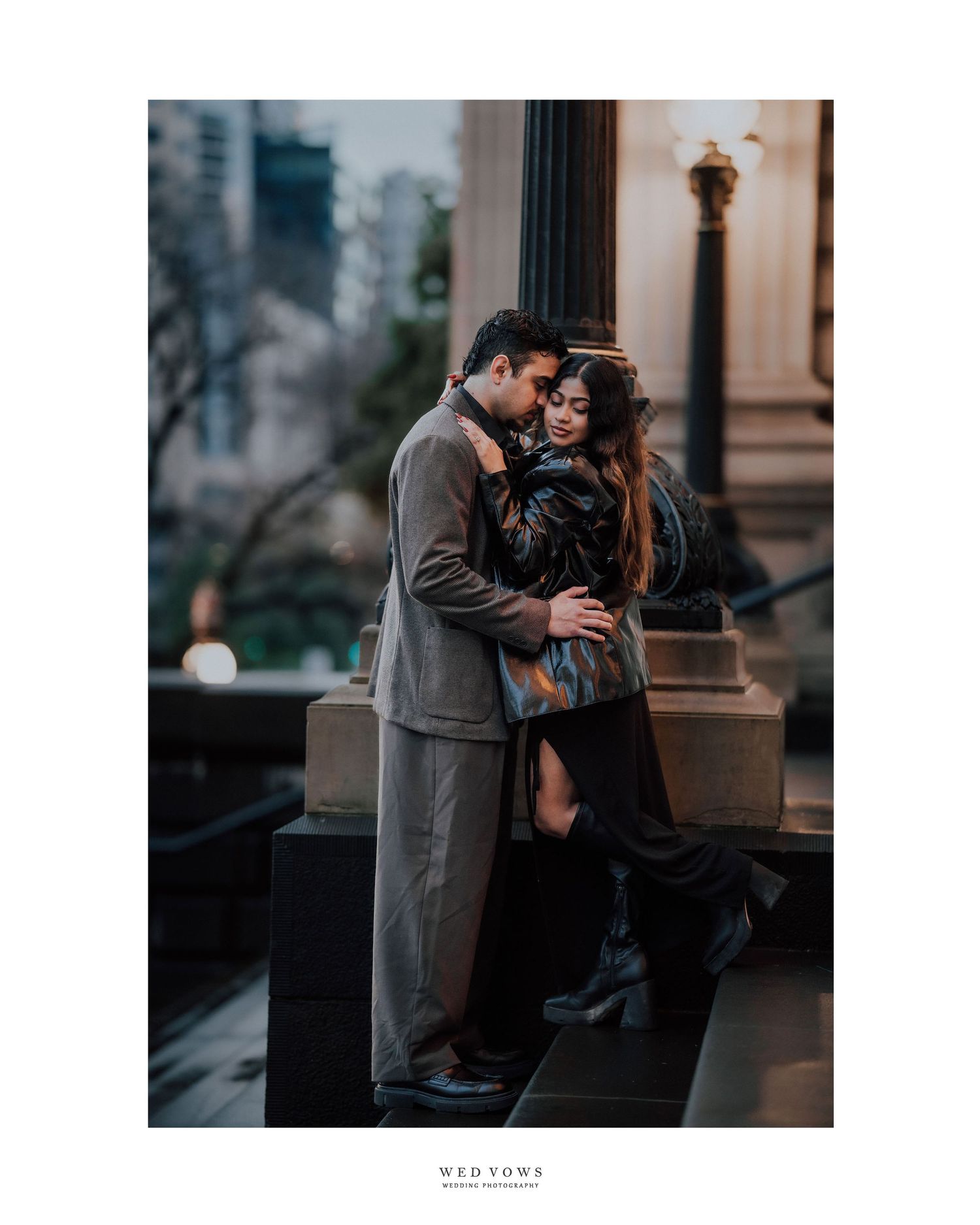Romantic couple embracing and kissing on a city terrace during a twilight engagement shoot.