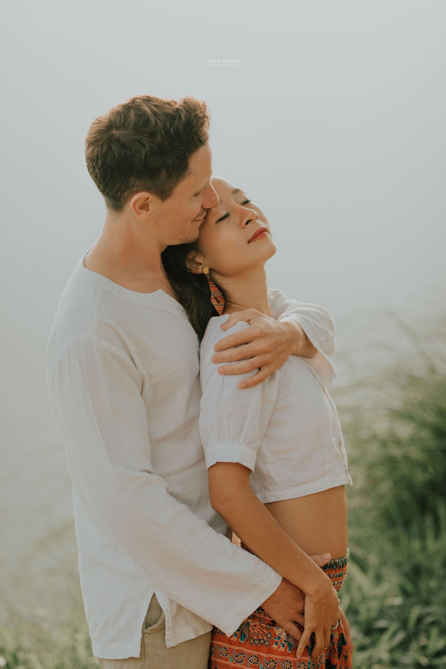 Couple embracing tenderly outdoors, woman leaning back with eyes closed in joy.
