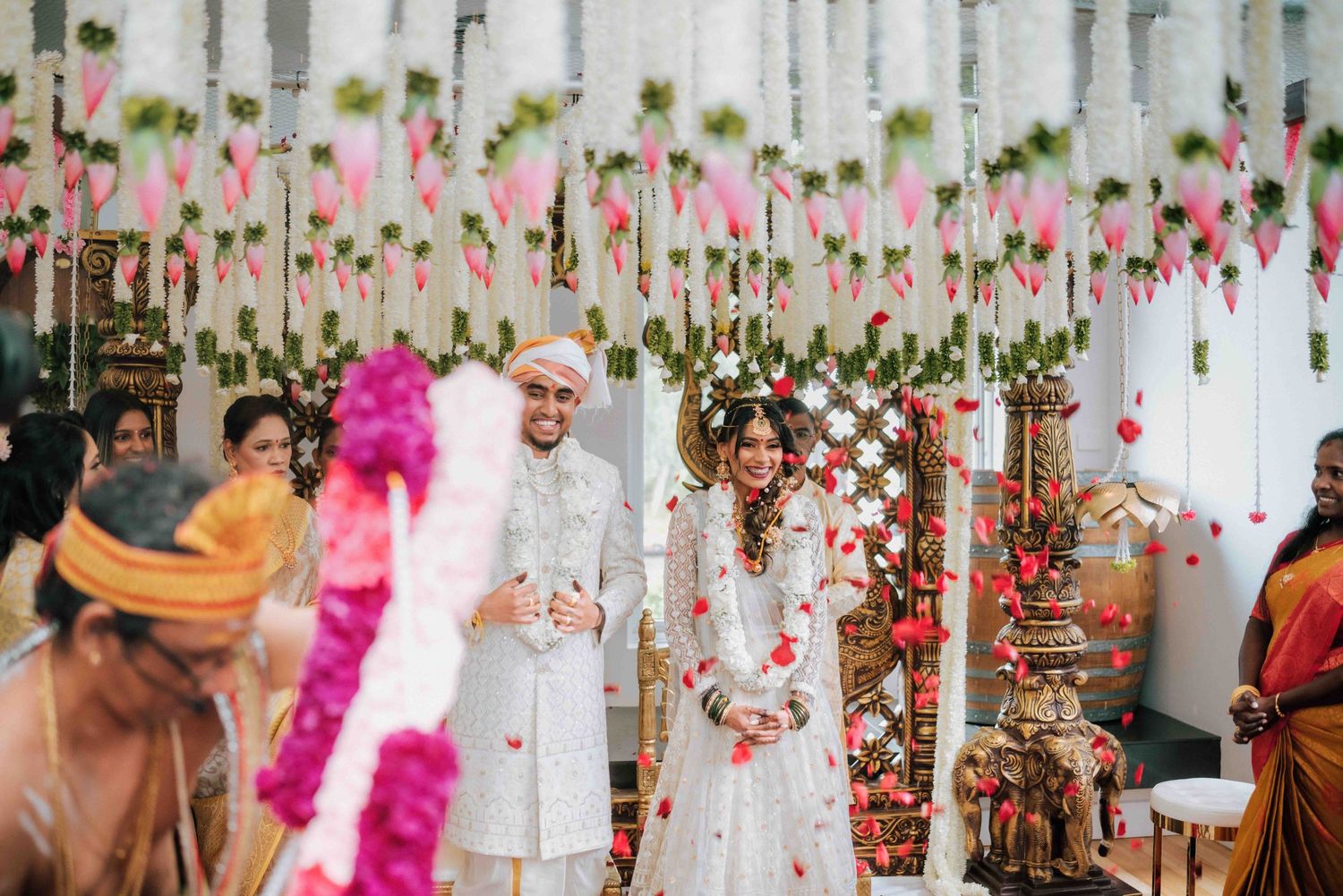 Hindu bride and groom walking together at floral decorated mandap during traditional wedding ceremony.