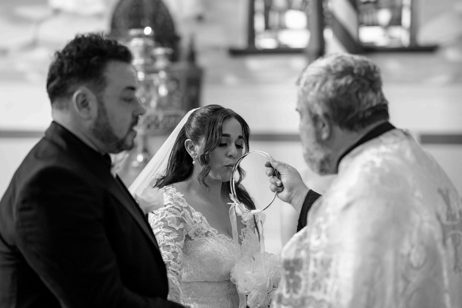Bride and groom receive blessing from priest during traditional church wedding ceremony.