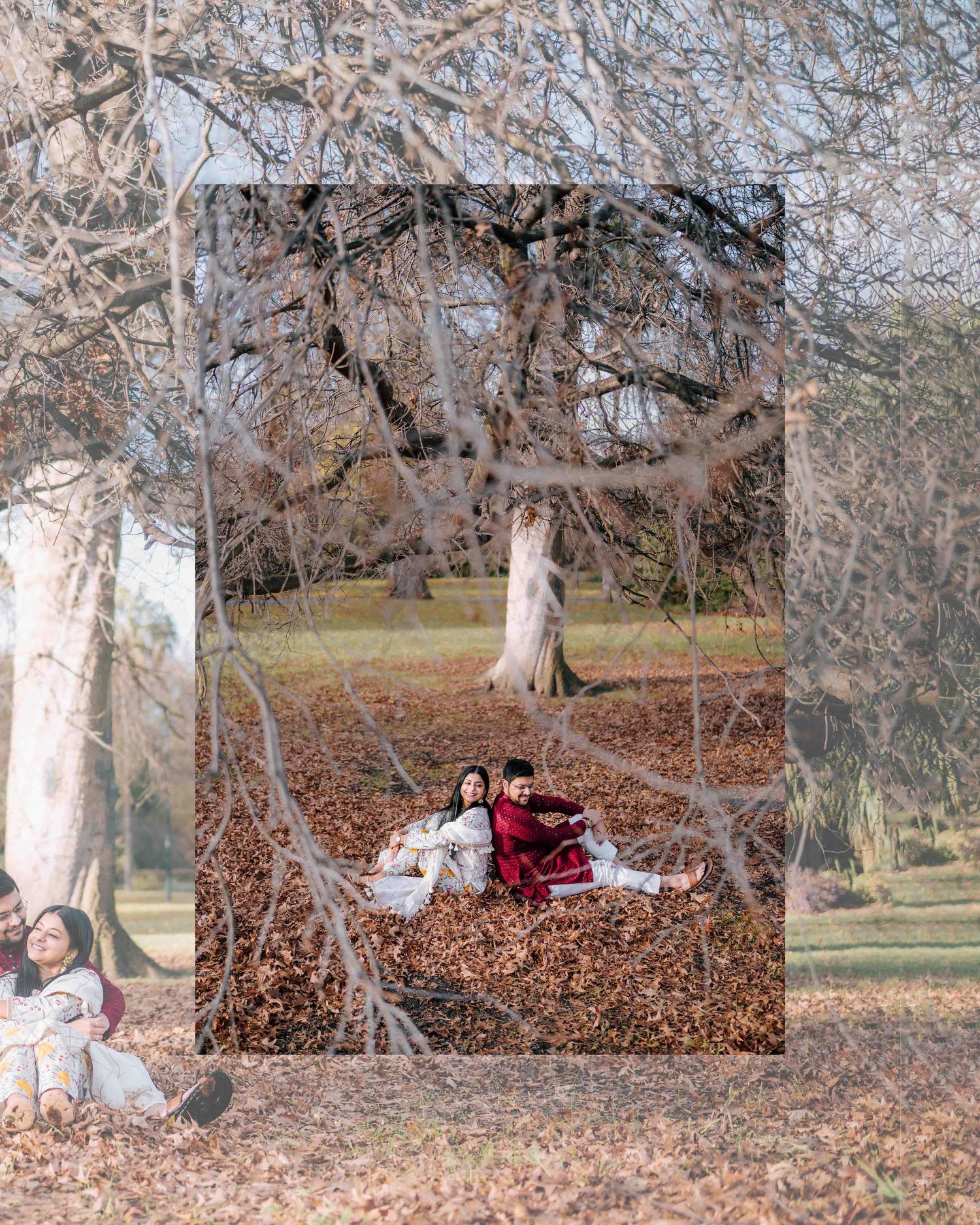 Couple in traditional Indian outfits sitting among autumn leaves beneath bare trees in a park setting.