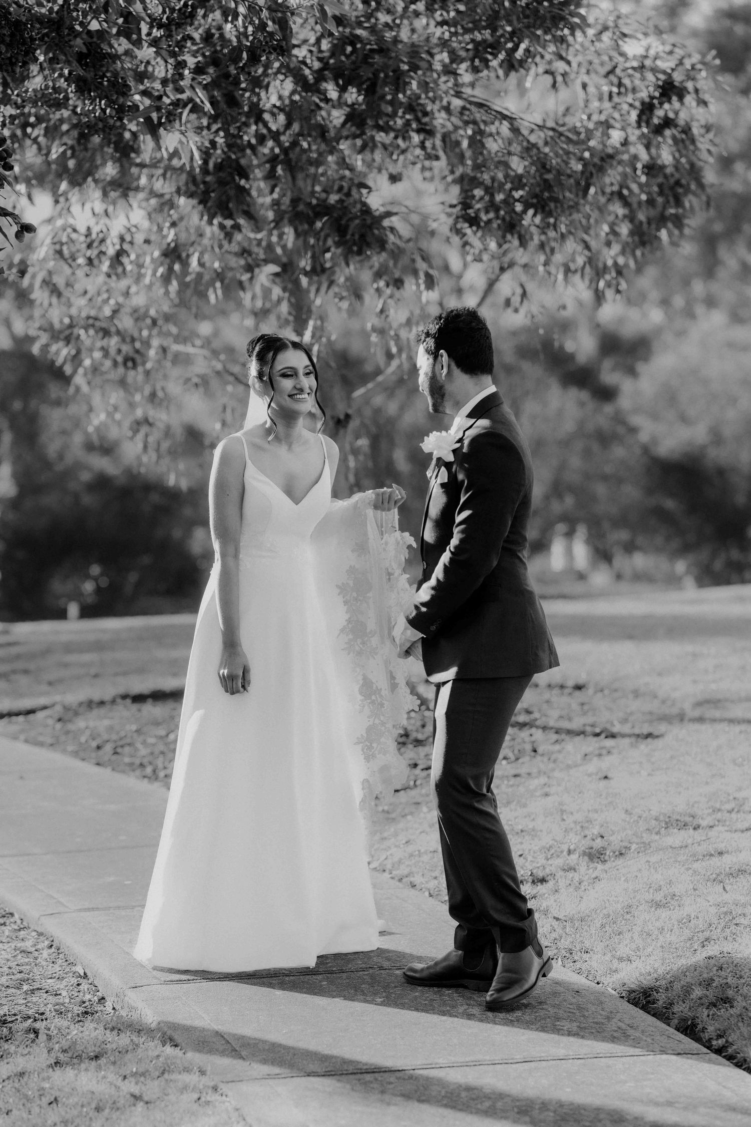 Black and white photo of bride and groom sharing first look moment on garden pathway.