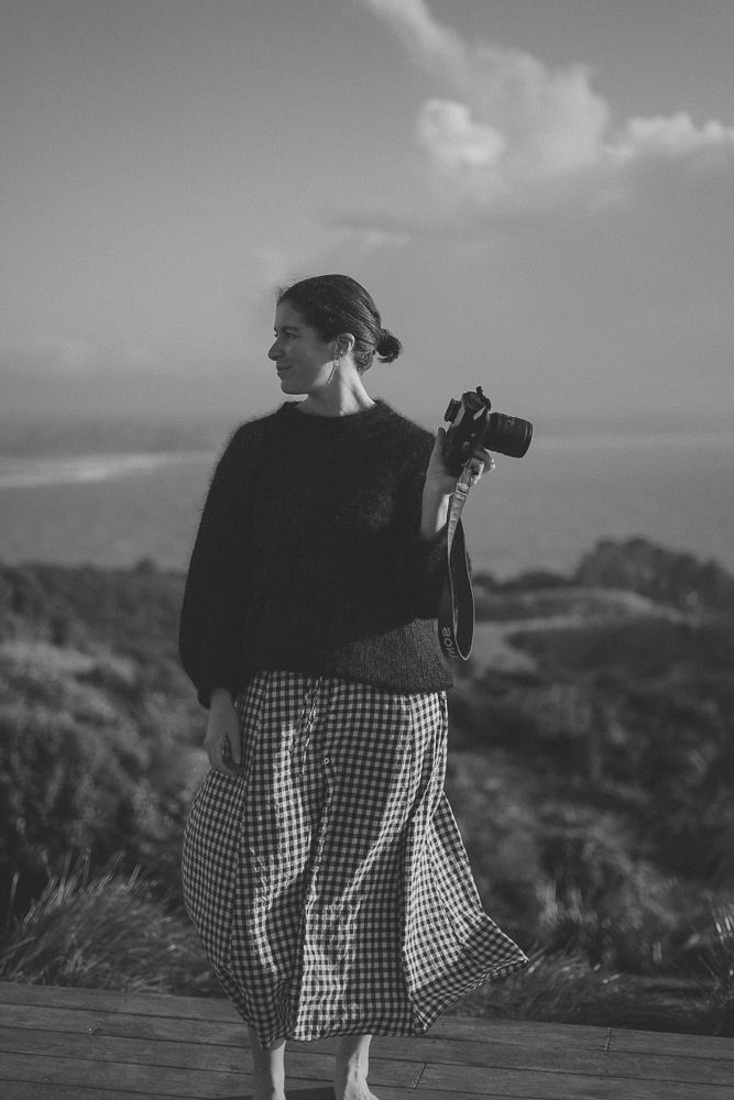 A portrait photographer stands in the afternoon sunshine on the West coast of new zealand.
