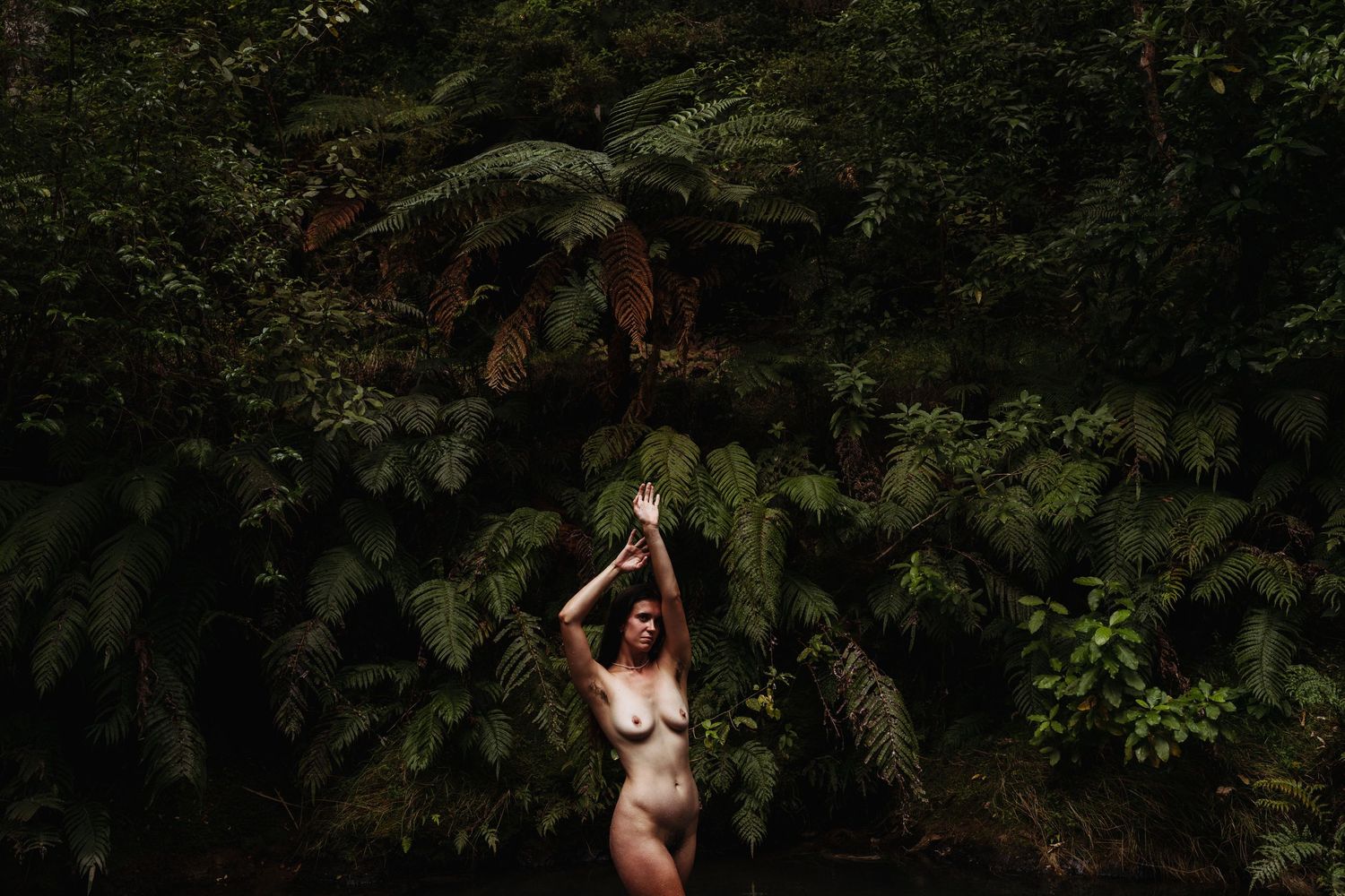 A woman stands elegantly amongst native New Zealand bush. Image created by Photography by Chloe