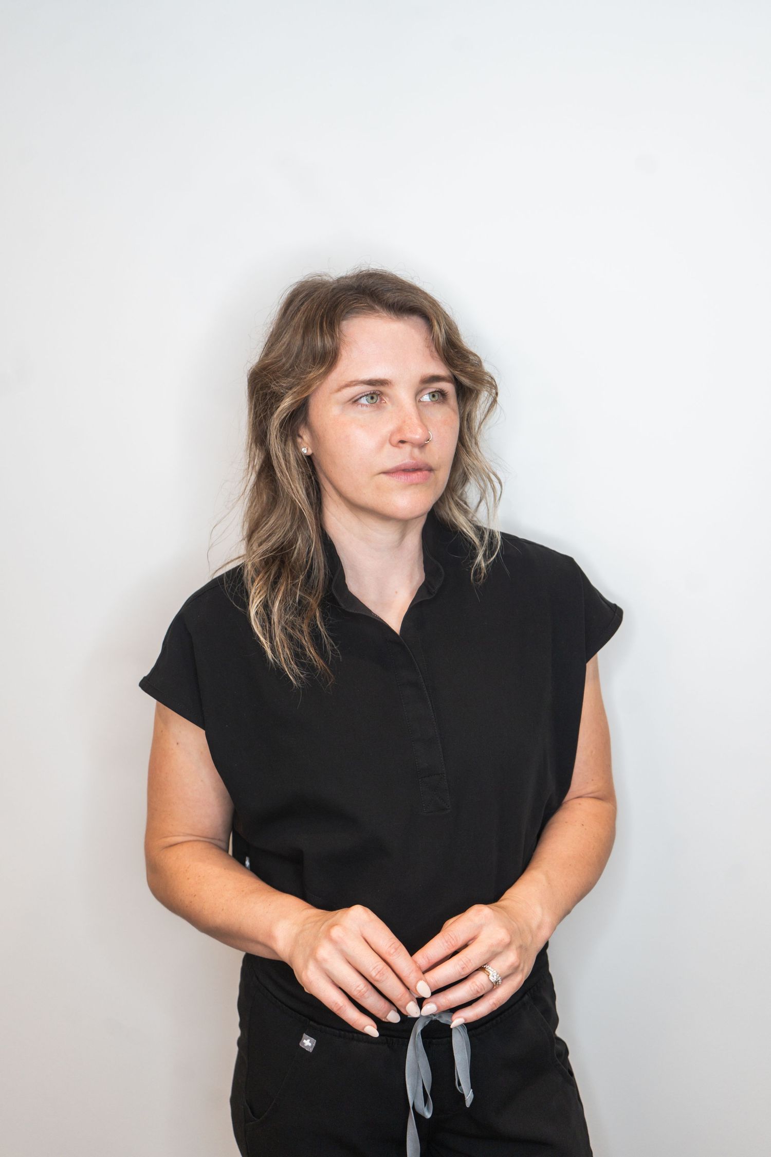 Four portrait photos of someone in a black sleeveless top against a light background looking in different directions.