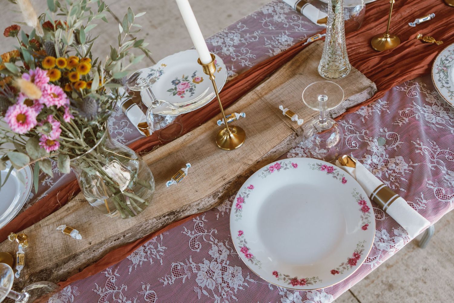 Elegant table settings with vintage floral plates, lace tablecloth, crystal glasses and pink roses create a romantic ambiance.