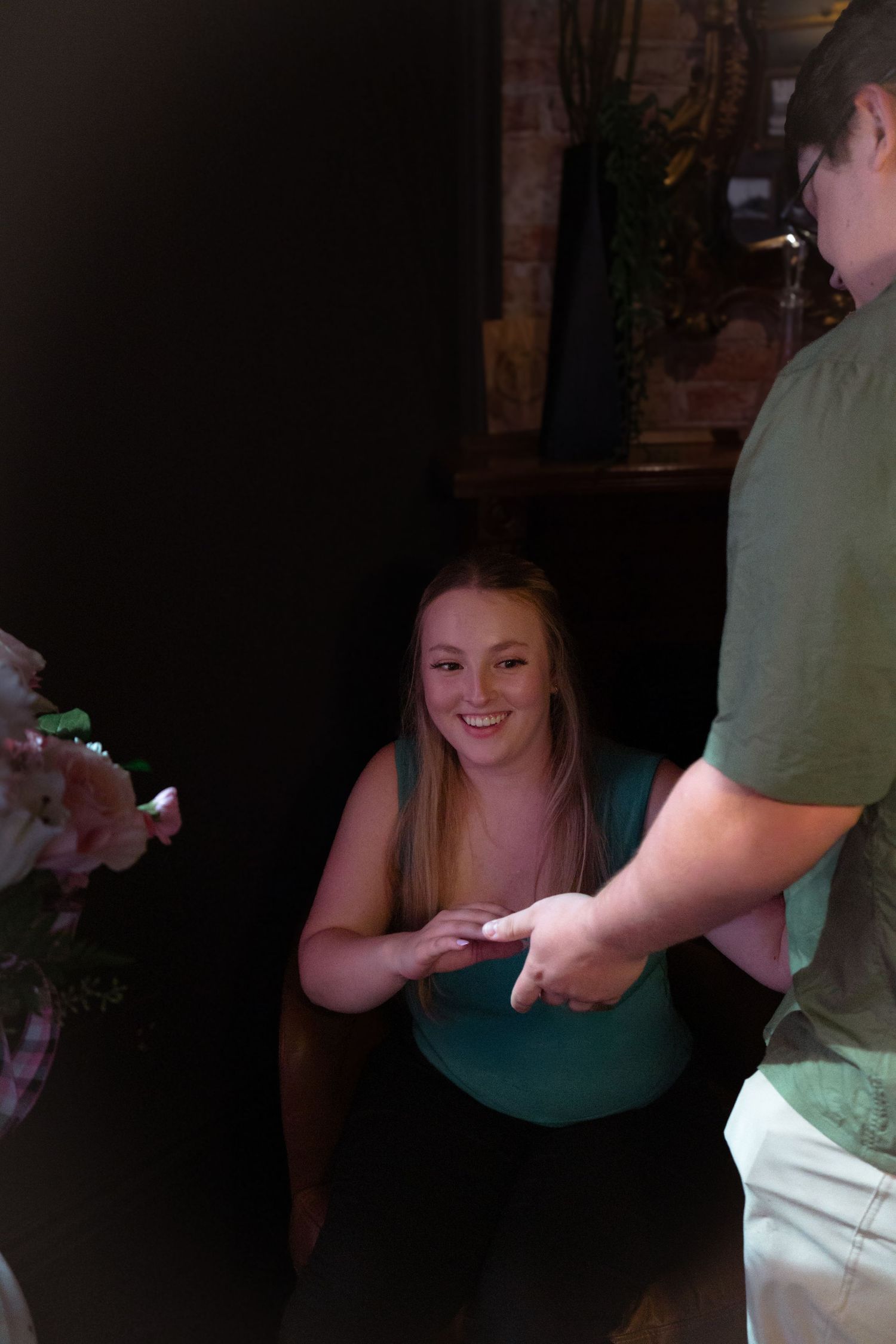 A tender moment during a proposal in a cozy restaurant setting with floral decorations.