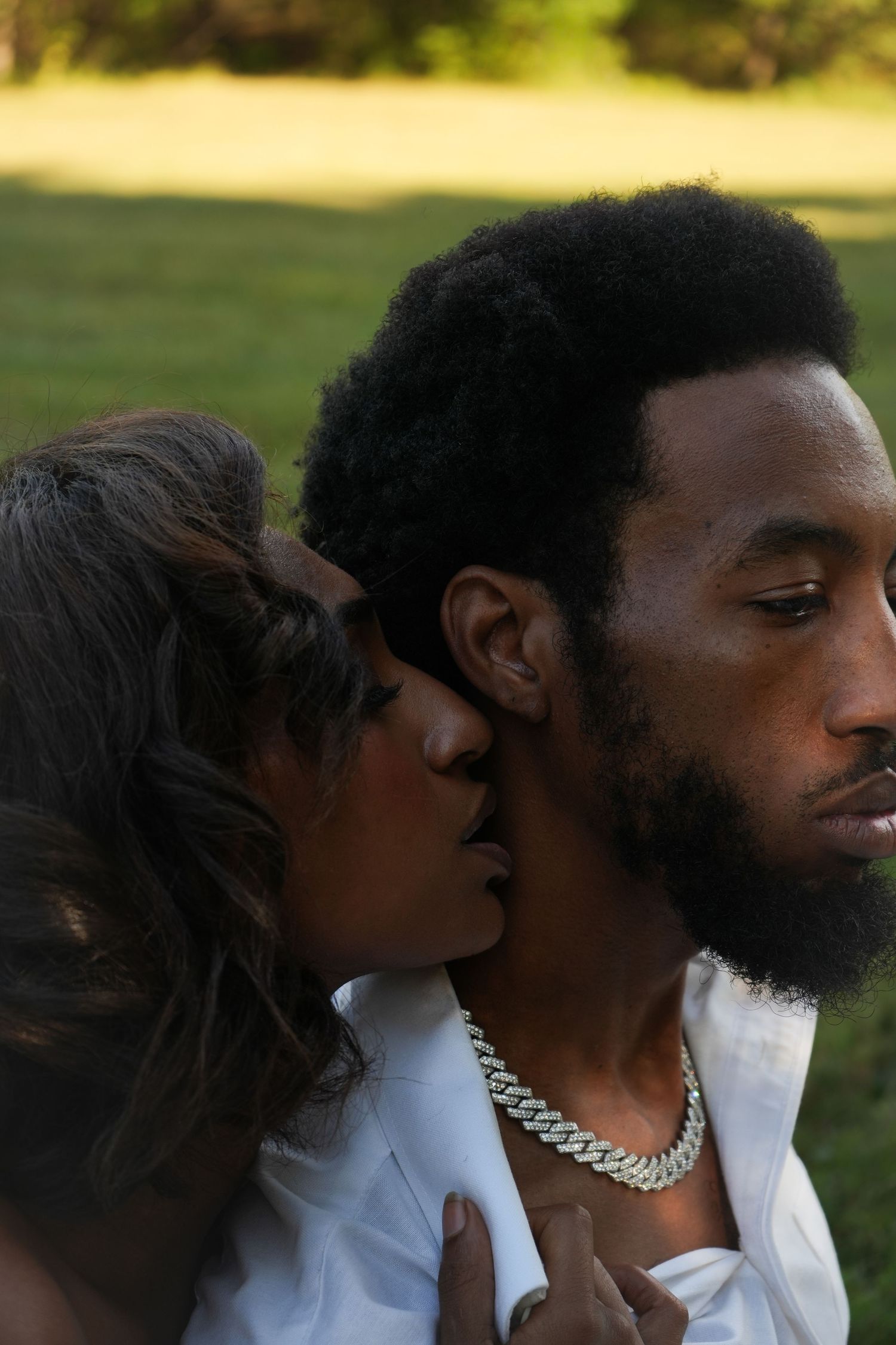 A series of intimate profile shots showing two people in white clothing with a silver chain necklace against a blurred background.