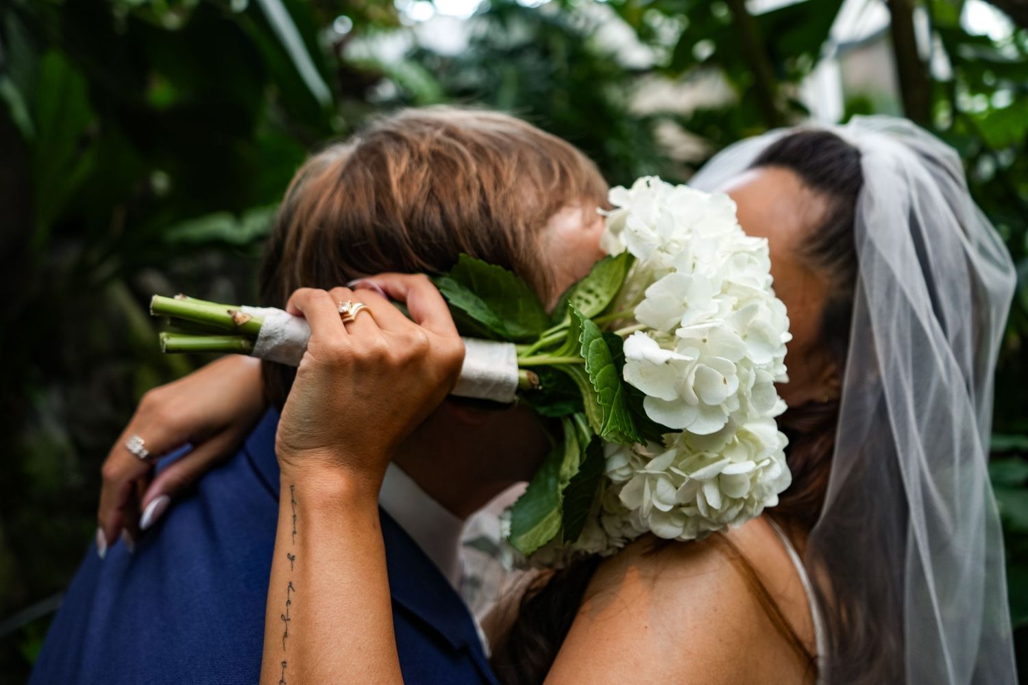 Wedding couple behind white rose bouquet in romantic pose.