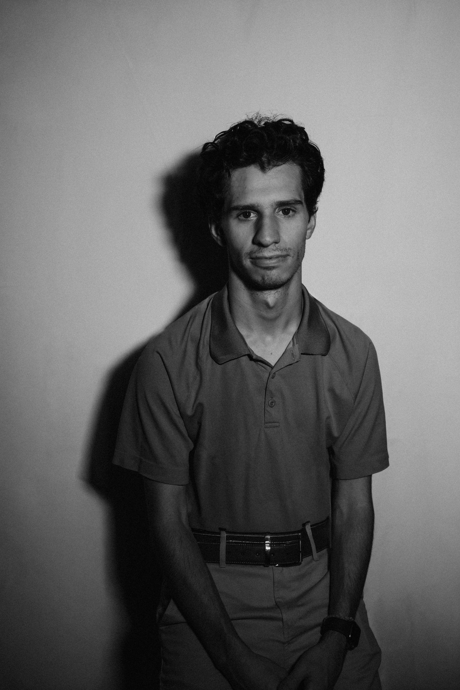 Black and white portrait series showing person in polo shirt with dramatic lighting and shadows against plain backdrop.