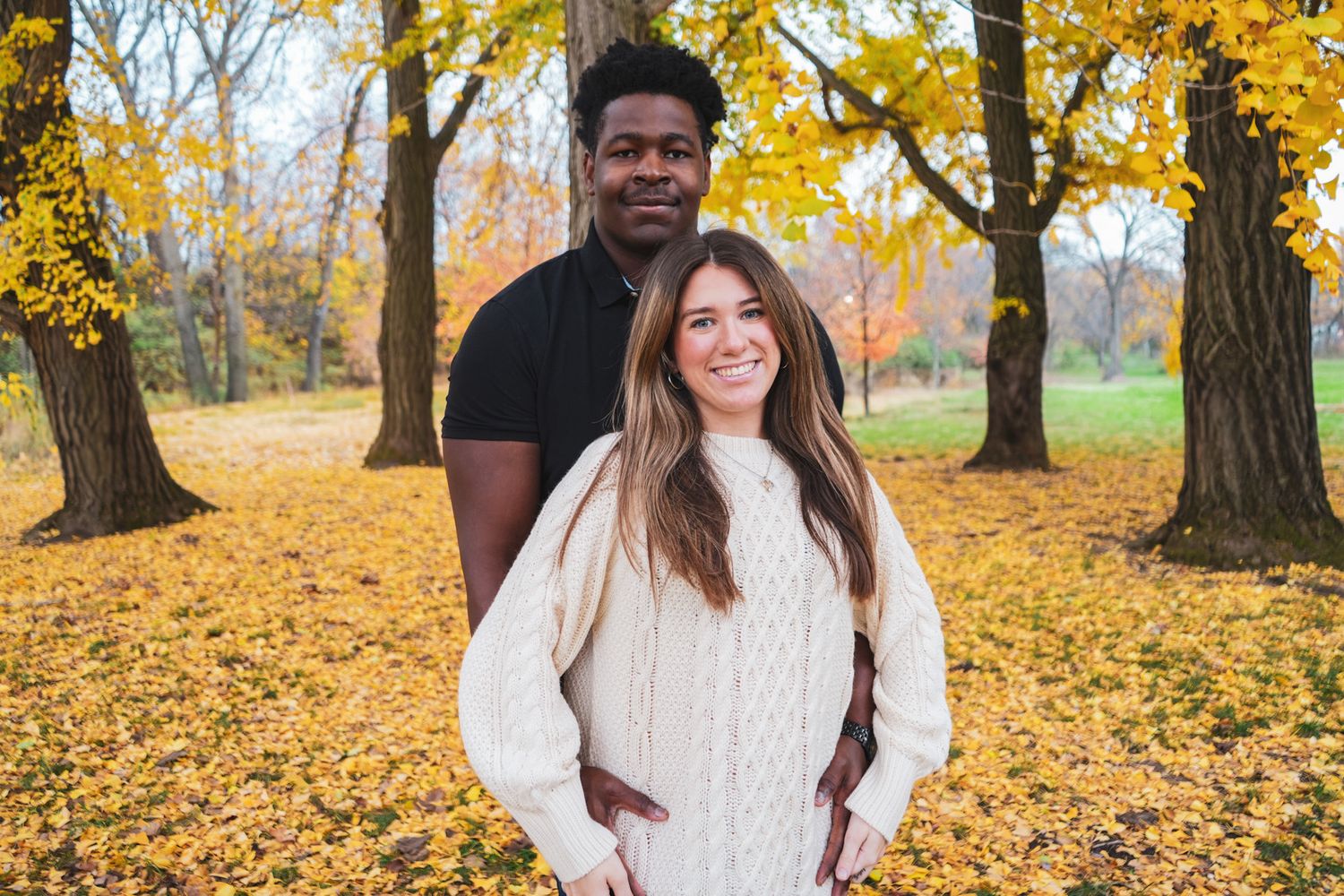 Autumn engagement photos with yellow fall foliage and trees in the background.