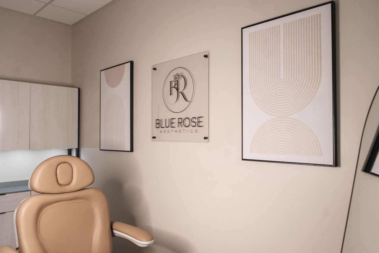Beige medical treatment chair in a modern spa room with minimalist wall art and Blue Rose logo signage.