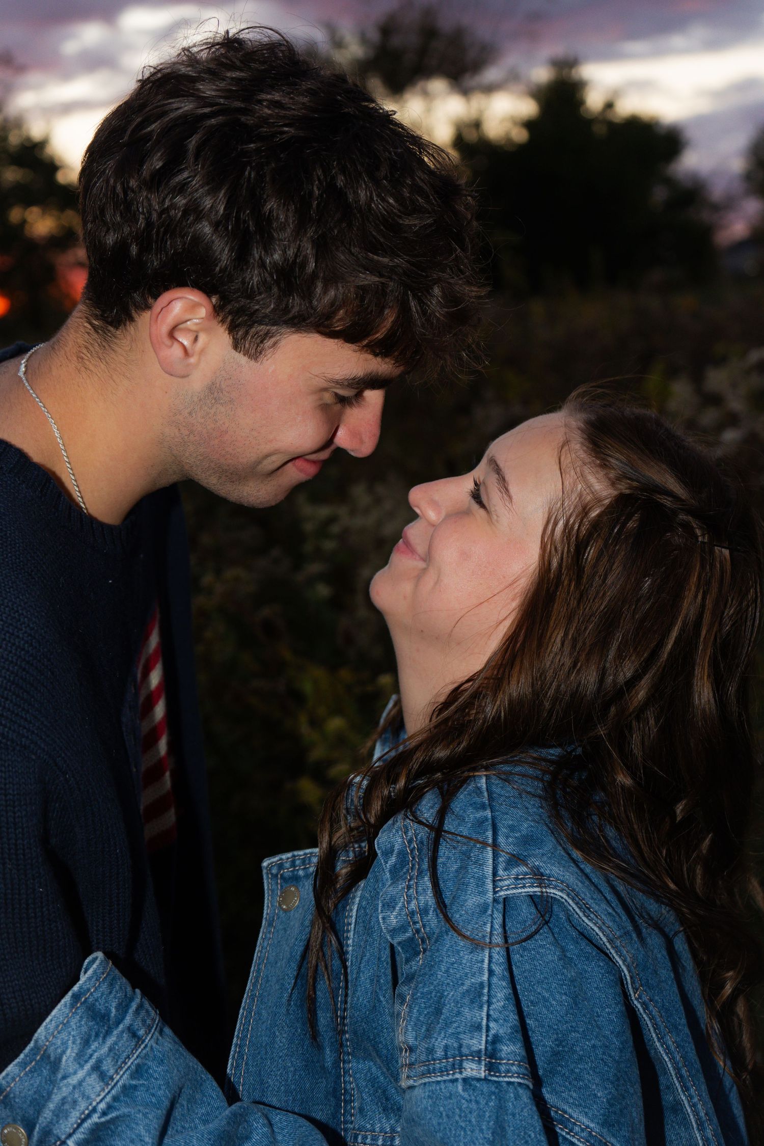 A romantic moment captured at sunset with two people in denim and navy attire.